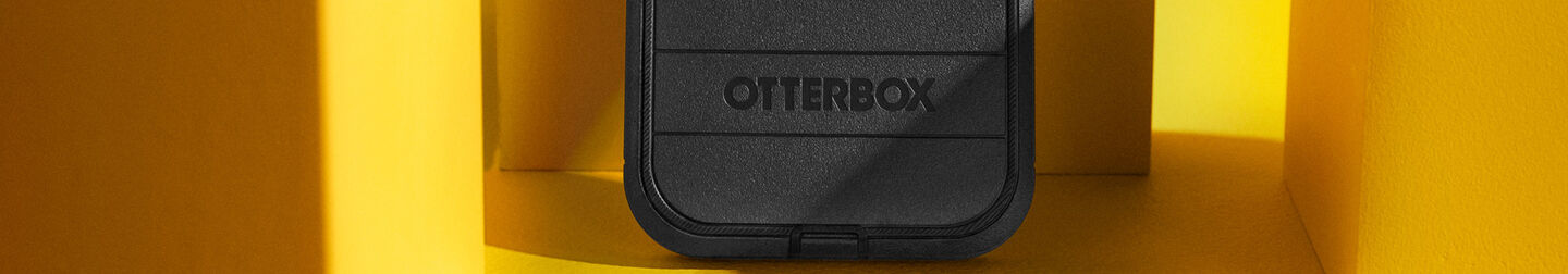 Black OtterBox Defender Series heavy duty protective iPhone case on yellow background