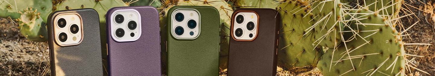 Four Cactus Leather iPhone cases leaned against a cactus