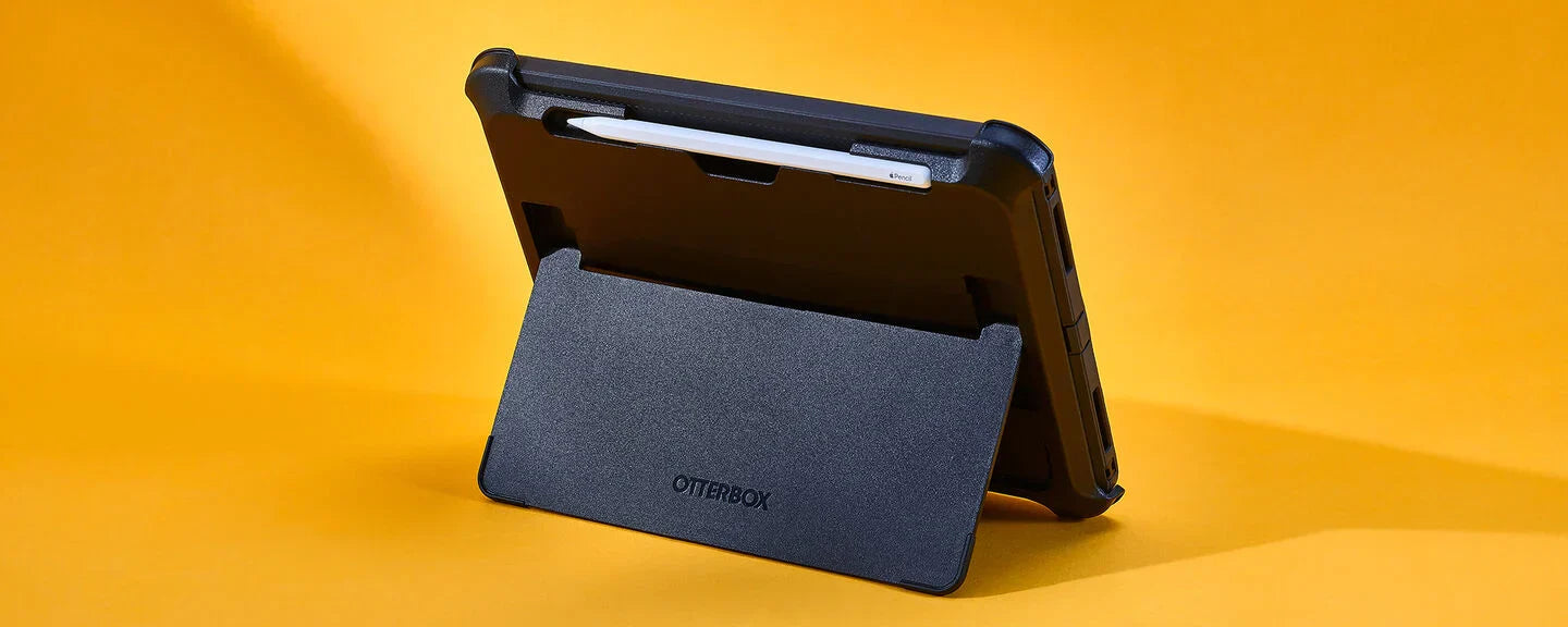 Black protective OtterBox Defender Series iPad case standing up on a yellow background