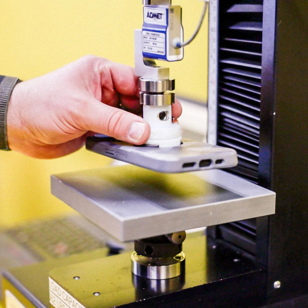 Hand holding a small cylindrical object above a machine with a yellow background