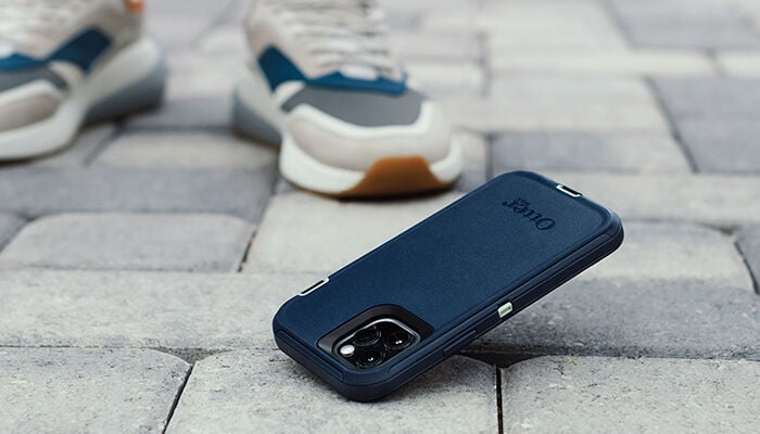 Blue phone case on a textured surface with sneakers in the background