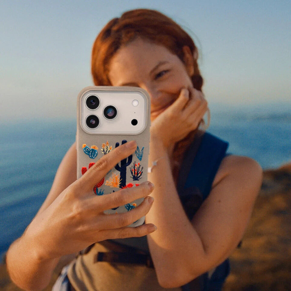Person holding a phone with a colorful case against a scenic background