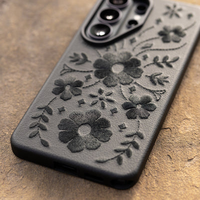 Black floral embossed Samsung phone case on a textured surface