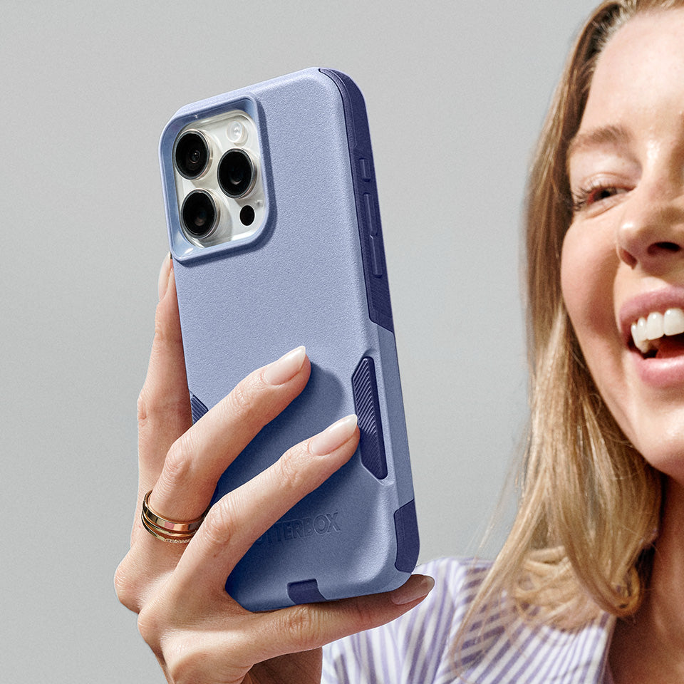 Person holding a phone with a purple case against a gray background