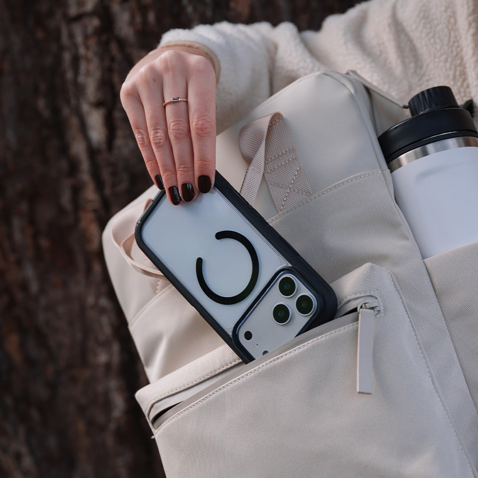 Person placing a phone with a clear case with black accents into a backpack.
