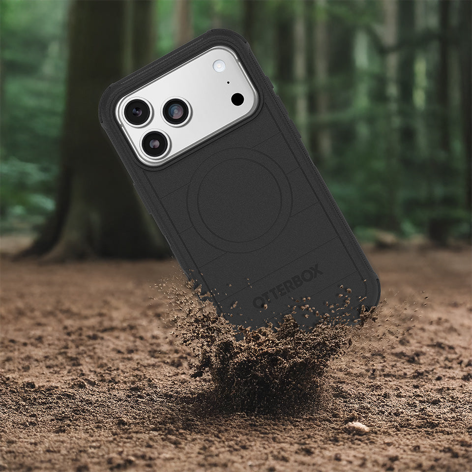 Black phone case being dropped into dirt, with a forest background.