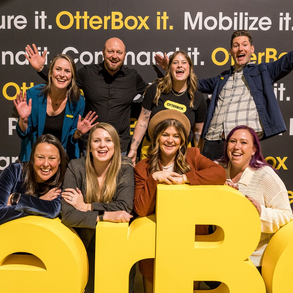 Group of people posing with large yellow letters spelling 'OR' against a branded background.